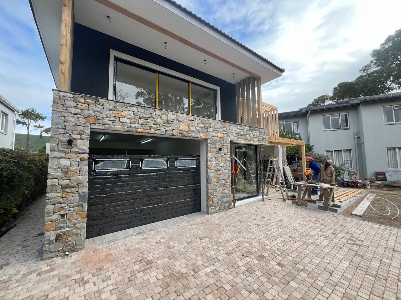 Dark garage door with a window strip at a stone-clad house