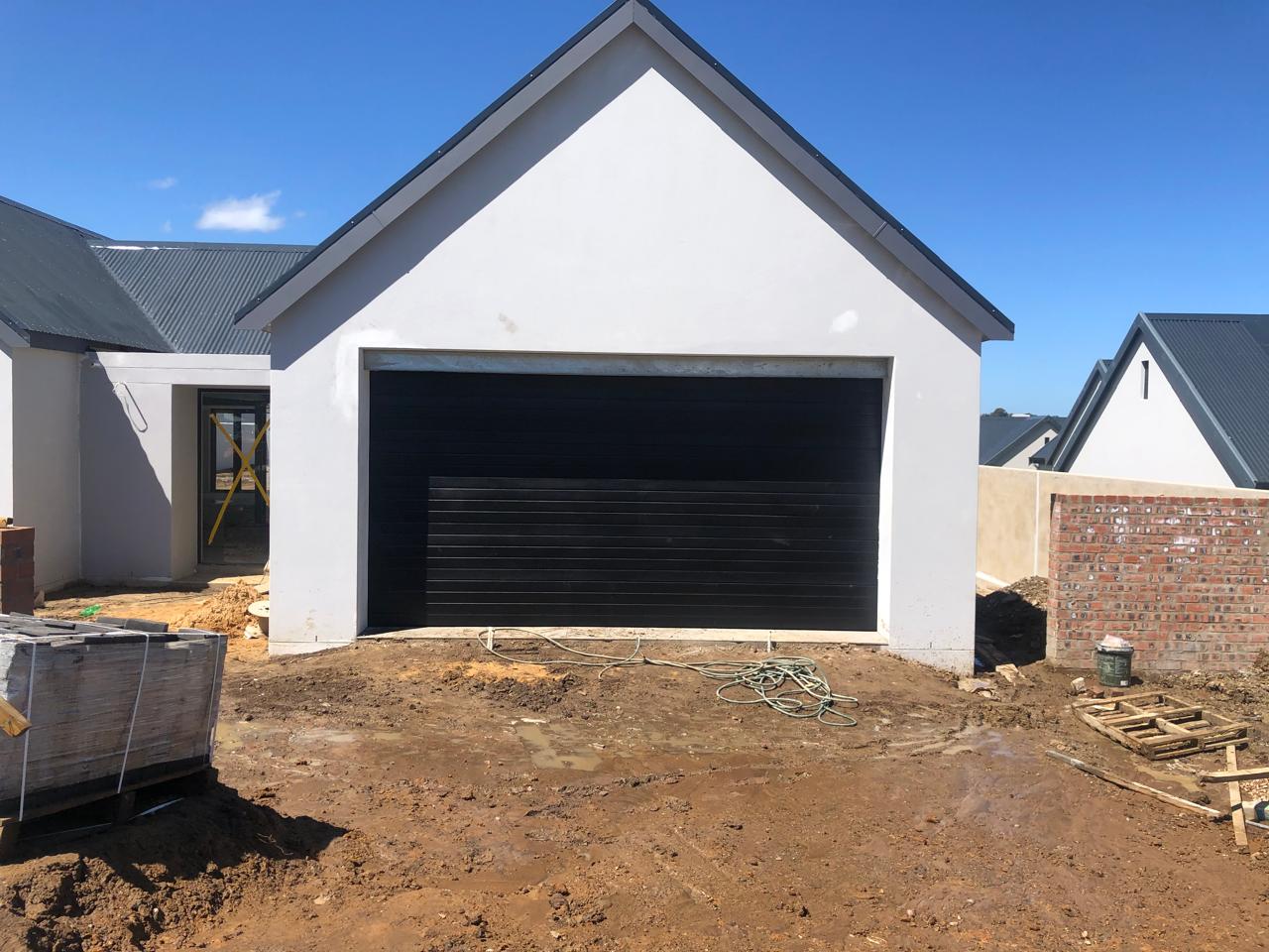 Dark garage door spanning a double-width opening at a new build