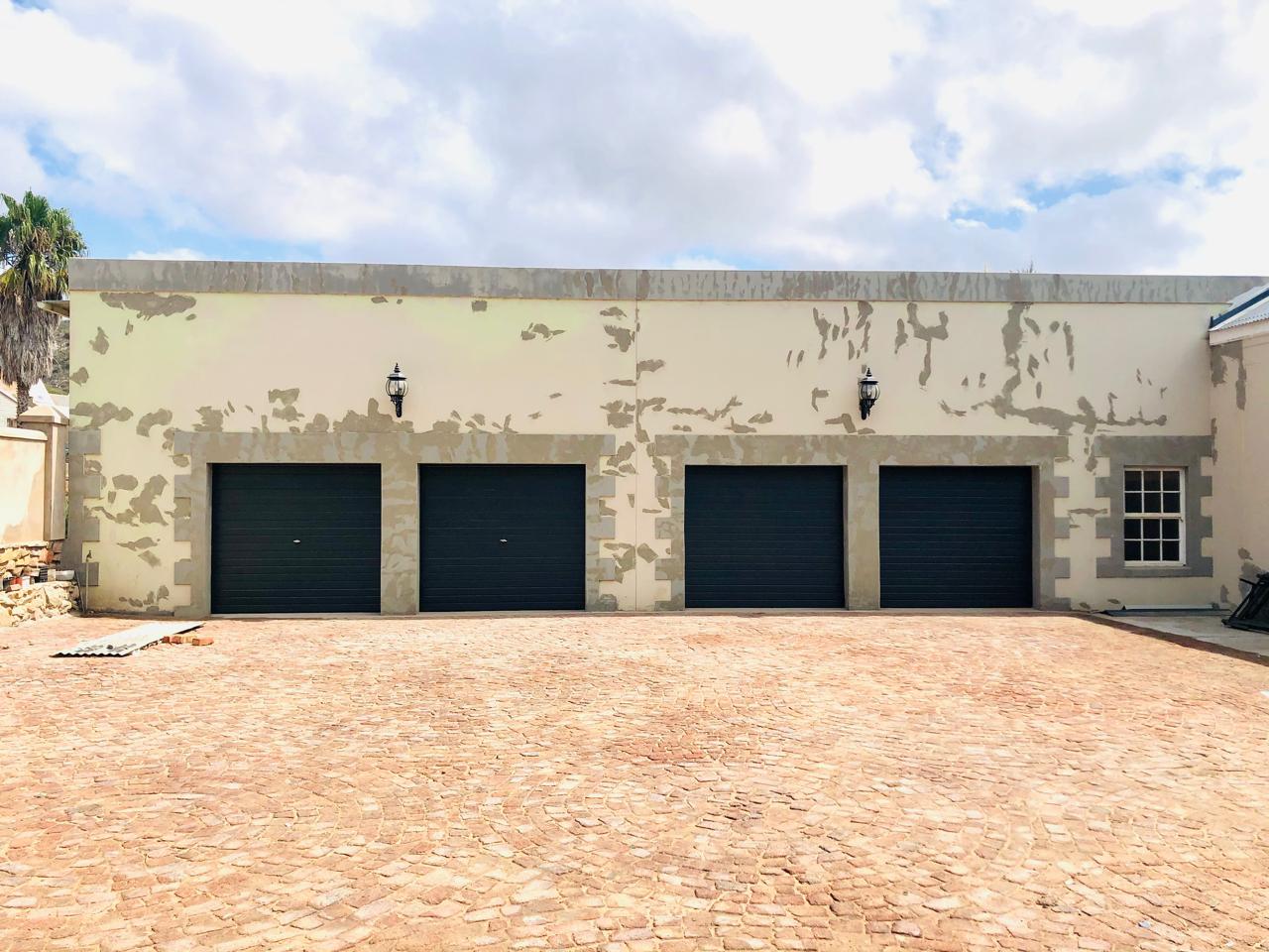 Four separate dark garage doors across a wide façade