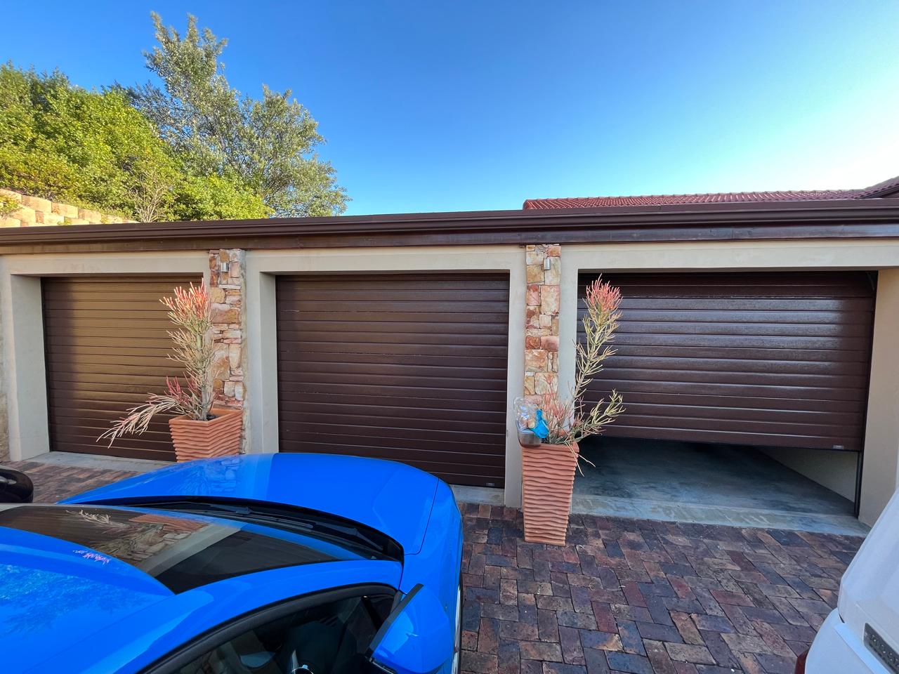 Three separate brown garage doors, one partly open